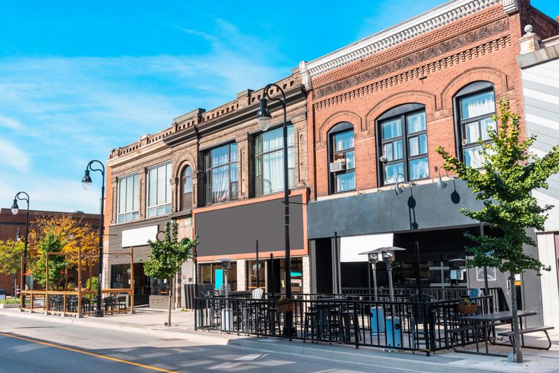 Traditional American brick buildings with restaurants and shops on ground level along a street in a downtown on a clear autumn day. St, Catharines, ON, Canada.