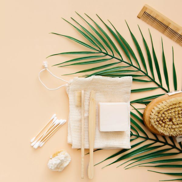 Eco-friendly bathroom essentials arranged on a peach background with greenery.