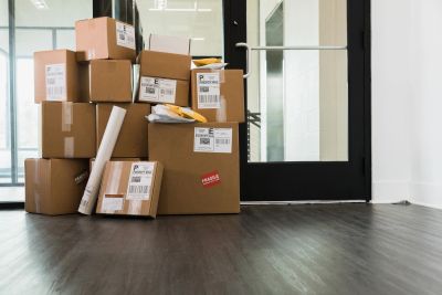 Stack of various cardboard boxes near a glass door inside a room.