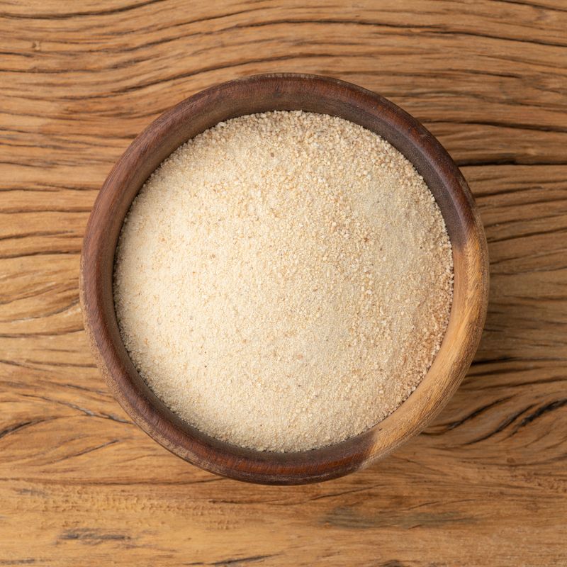 Manioc flour in a bowl over wooden table.