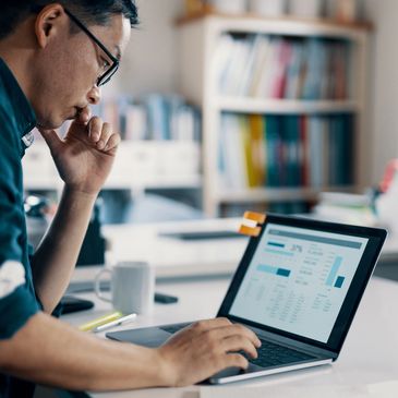 Man analyzing financial data on a laptop in a home office.