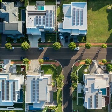 Aerial view of a suburban neighborhood with solar panels on rooftops and tree-lined streets.