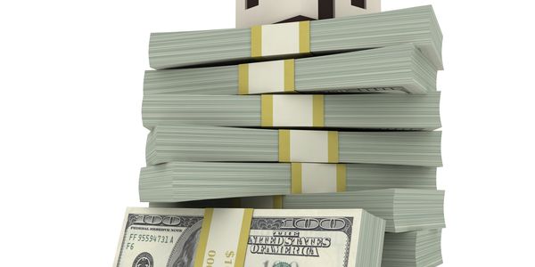 Small house model on top of large stacks of hundred-dollar bills.