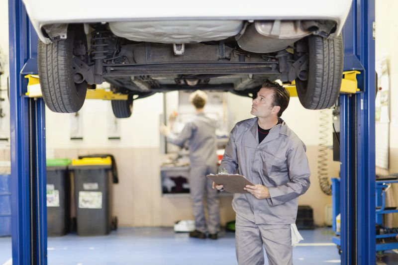 Mechanic examining underside of car