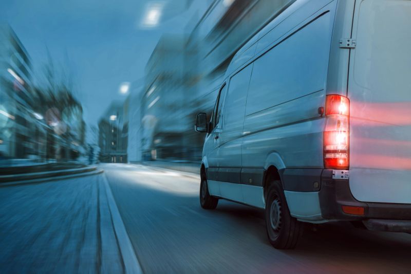 Rear view of a fast driving van in a city at night. Motion blurred background.