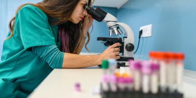 Scientist examining samples under a microscope.