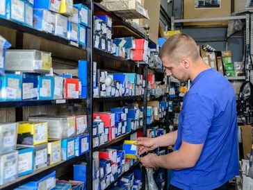 Man organizing boxes on shelves in a storage room.