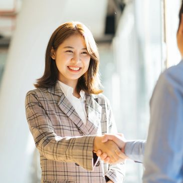 Two professionals shaking hands in a bright office setting.