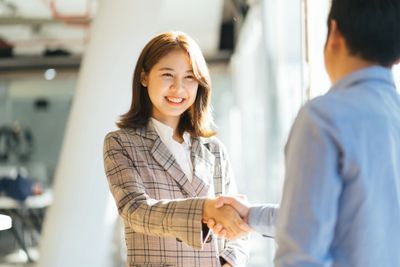 Two professionals shaking hands in a bright office setting.