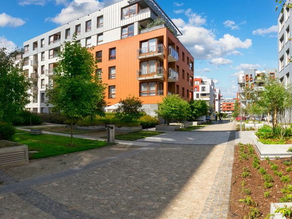 Modern residential buildings with greenery and clear blue sky.