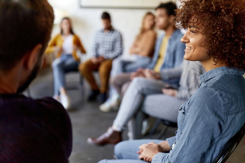 Young happy female freelancer and her colleagues having a group therapy in the office.