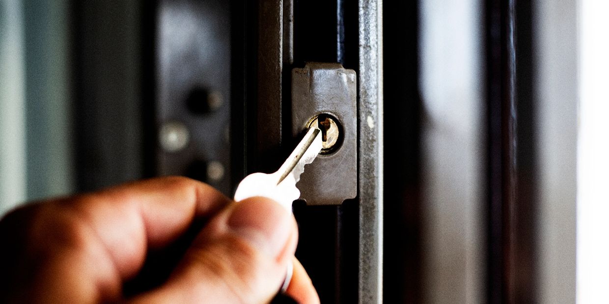 Hand inserting a key into a door lock.