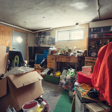 Cluttered basement filled with boxes, tools, and various household items under dim lighting.