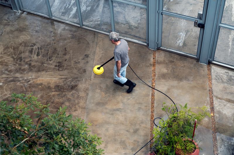 Man washing his concrete floor using high pressured water cleaner.
