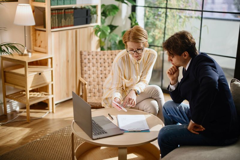 Mature woman meeting with a financial consultant to discuss paperwork at home