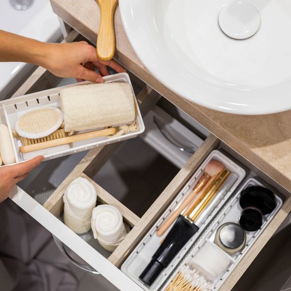 Organized bathroom drawer with towels, brushes, and makeup tools.