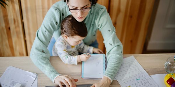 Mother working on laptop with child on lap.