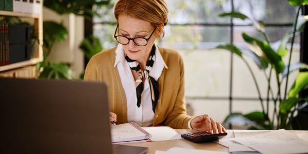 Woman working at desk with calculator and notebook.