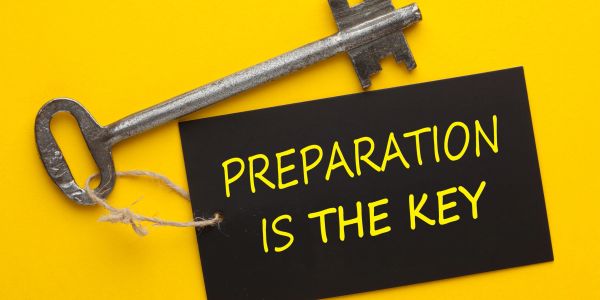 A key and a card saying "Preparation is the key" on a yellow background.