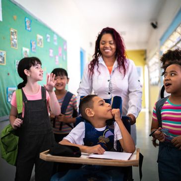 Teacher happily walking with diverse students in a school hallway.