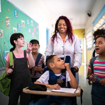 Teacher smiling with diverse students in a school hallway.