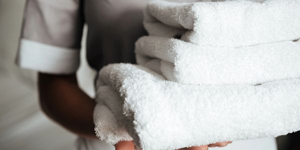Person holding folded white towels.