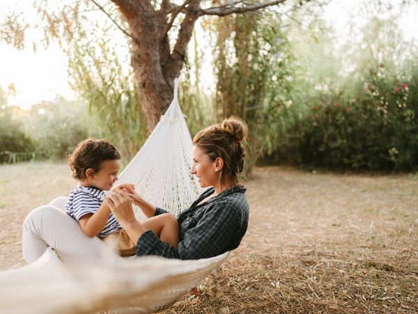 A mother and child enjoying time together in a hammock outdoors.