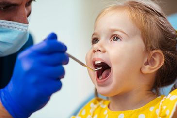 Doctor checking a little girl's throat.