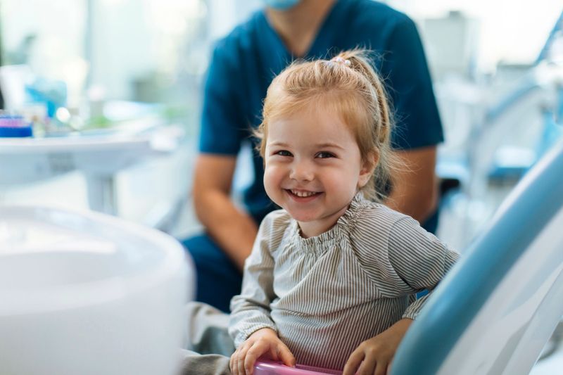 Portrait shot of a young smiling girl sitting in a dental chair in her dentists office