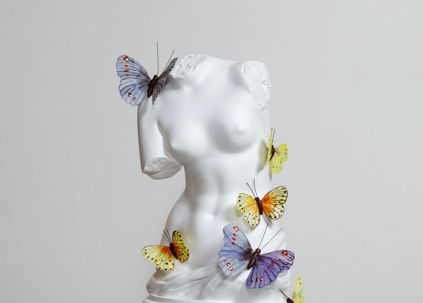 Escultura femenina con mariposas de colores.