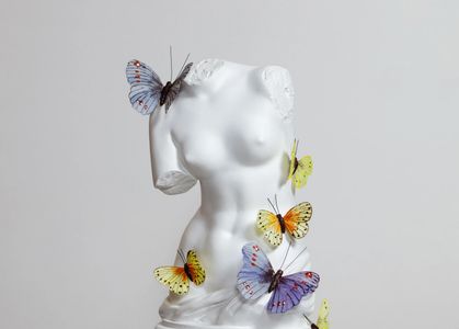 Escultura femenina con mariposas de colores.