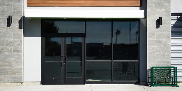 Modern black glass door entrance with gray stone walls.