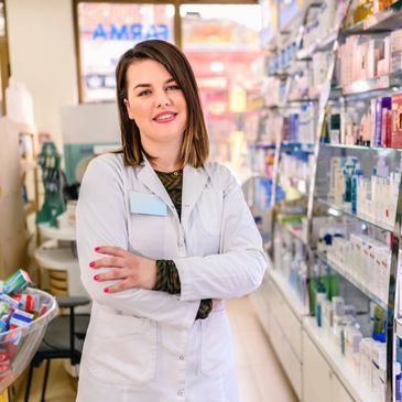 Pharmacist confidently standing in a pharmacy aisle with arms crossed.