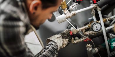 Technician fixing plumbing pipes with a wrench.