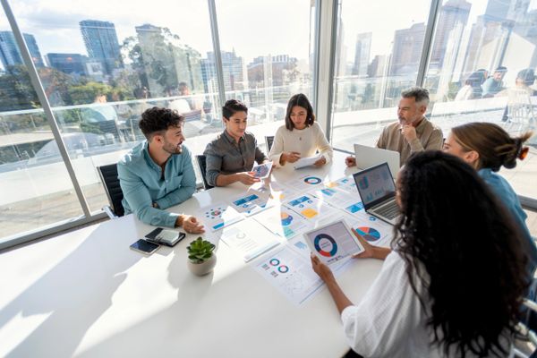 A diverse group discussing business charts in a bright office.