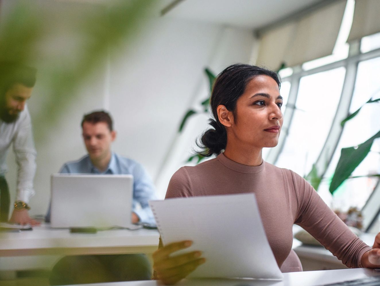 A woman working at a desk with papers and a keyboard in an office.