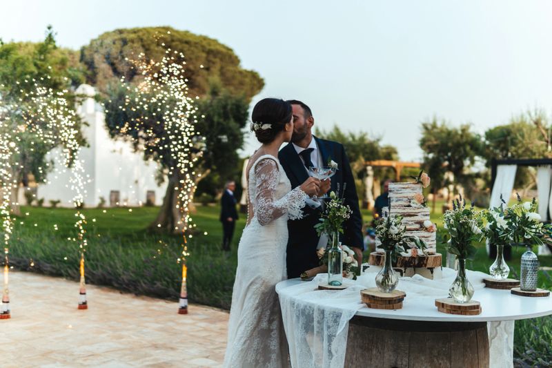 Cake cutting during wedding ceremony with fireworks in the background