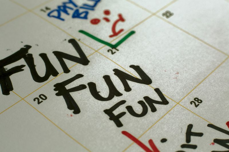 Written word reminders marked on a paper calendar with a color pen marker with words fun.