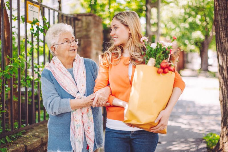 Smiling granddaughter is doing shopping for her grandmother