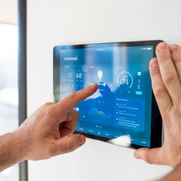 Person controlling smart home system on a wall-mounted tablet.