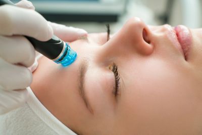 Woman receiving a facial treatment with a skincare device.