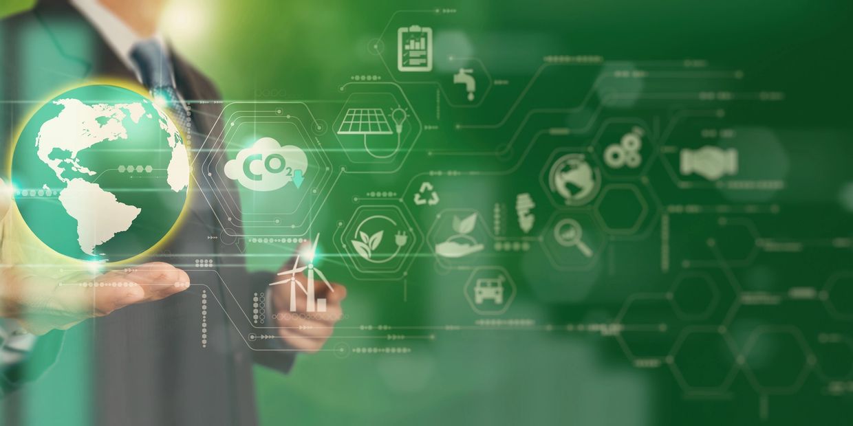 Businessman holding a digital globe with eco-friendly technology icons.