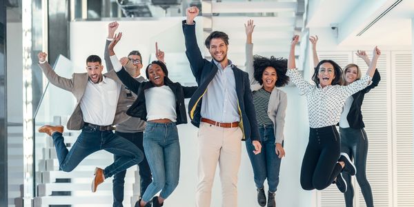 A group of people cheering and raising their arms after a successful software implementation.