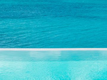 Infinity pool overlooking a serene blue ocean.