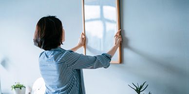 Woman hanging a mirror on a wall.
