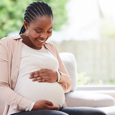 Pregnant woman smiling and touching her belly.
