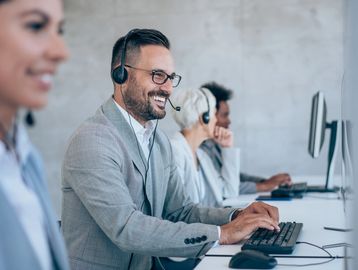 Smiling customer service representatives wearing headsets at their desks.