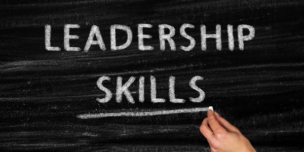 Hand writing 'LEADERSHIP SKILLS' on a chalkboard.