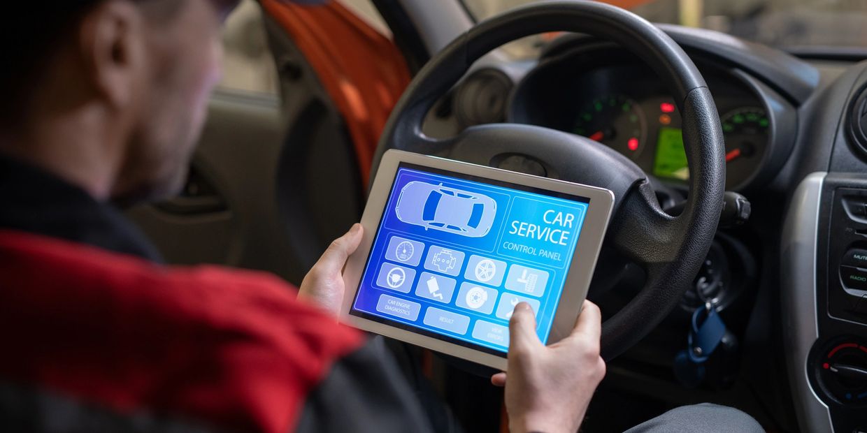 Car service worker is performing a car inspection while using the Power Apps app on tablet. 