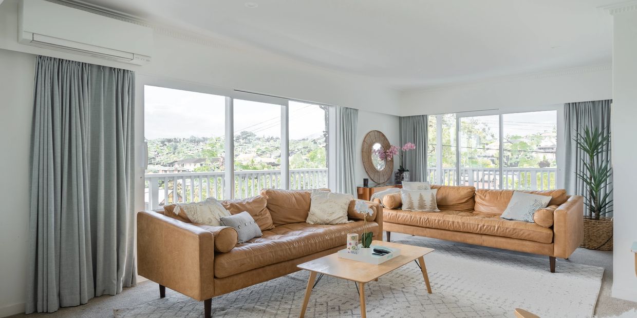 Bright living room with tan leather sofas and large windows.